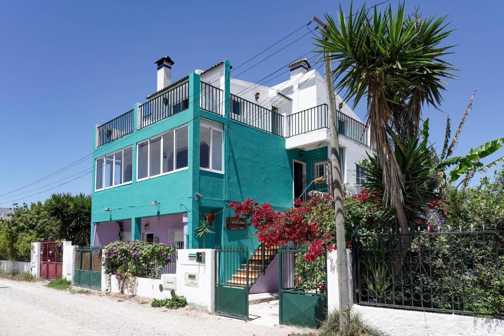 una casa blu e bianca con una palma di Natural Mystic Hostel a Costa da Caparica