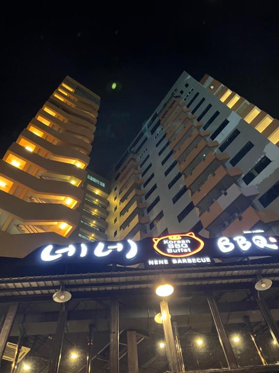 dos edificios altos por la noche con un cartel delante en Mall Suites Hotel, en Bangkok