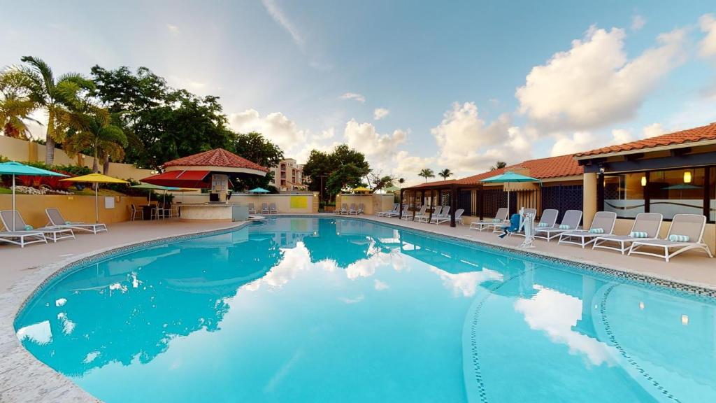 a large blue swimming pool with chairs and umbrellas at Park Royal Homestay Club Cala Puerto Rico in Humacao