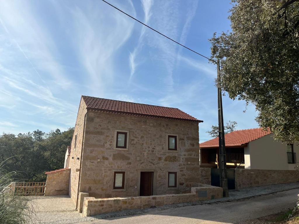 an old stone house on the side of a street at Quinta do Carvalho Cerquinho in Louriceiras de Baixo