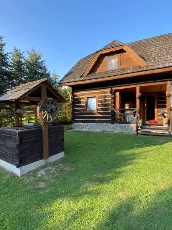a log cabin with a windmill in the yard at Chata Sanna in Lesko