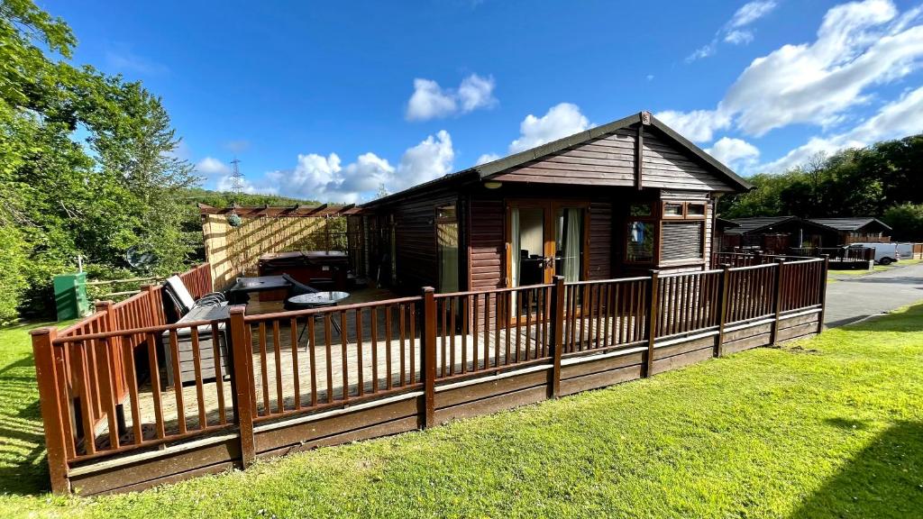 a house with a wooden fence in the yard at Conkers Lodge for 6 with Hot Tub & Secluded Decking - Spa Resort in Devon in Chudleigh