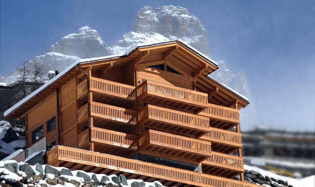 una cabaña de madera con una montaña cubierta de nieve en el fondo en La Cresta Chalet en Breuil-Cervinia