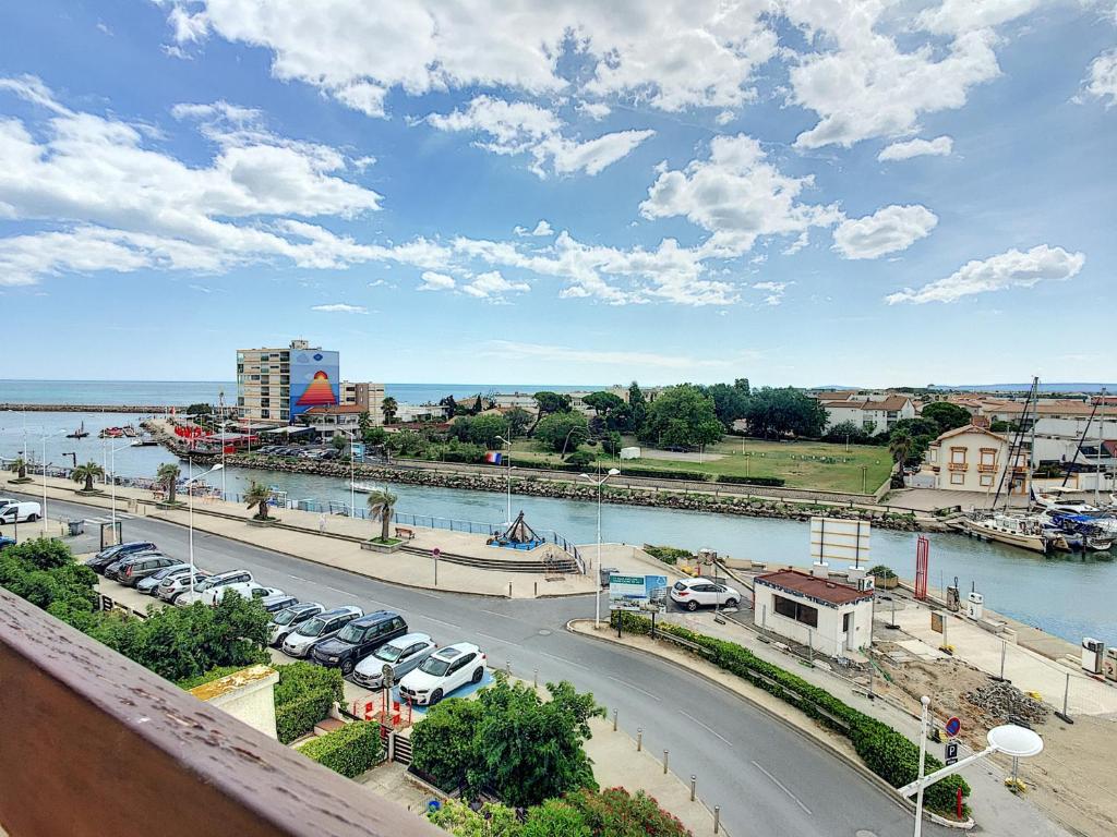 - une vue sur une ville avec des voitures garées à côté d'une rivière dans l'établissement Appartement T2 avec Terrasse, Climatisation et Parking - FR-1-715-22, à Mauguio