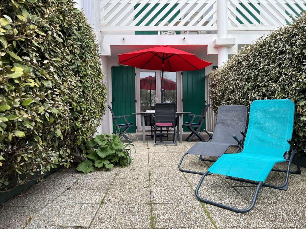 d'une terrasse avec une table, des chaises et un parasol rouge. dans l'établissement Appartement Matha, 2 pièces, 4 personnes - FR-1-246A-225, à La Cotinière