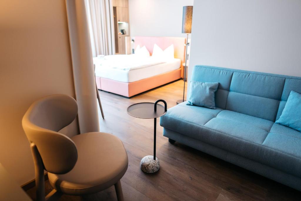 a living room with a blue couch and a bed at City Park Hotel in Frankfurt Oder