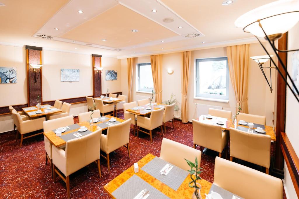 a restaurant with tables and chairs and windows at City Park Hotel in Frankfurt Oder