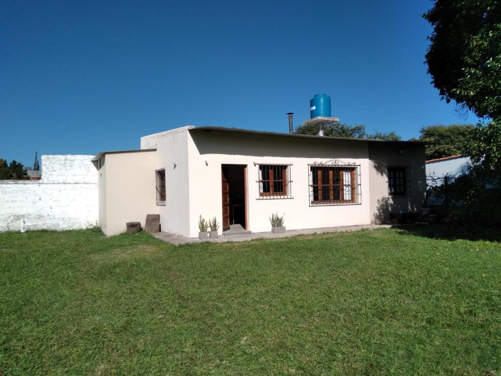 una pequeña casa blanca con un patio de césped en La casita de Cerrillos en Salta