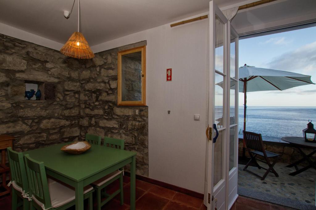 a dining room with a green table and an umbrella at Casa do Lado in Povoação