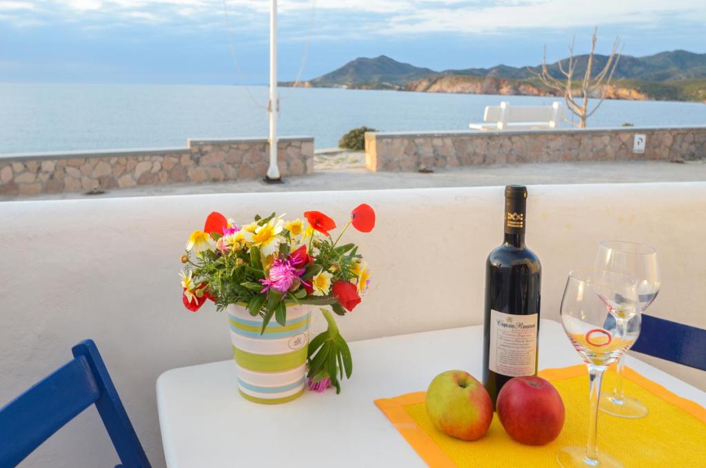 uma garrafa de vinho e um vaso de flores sobre uma mesa em Villa Mary Elen em Pollonia