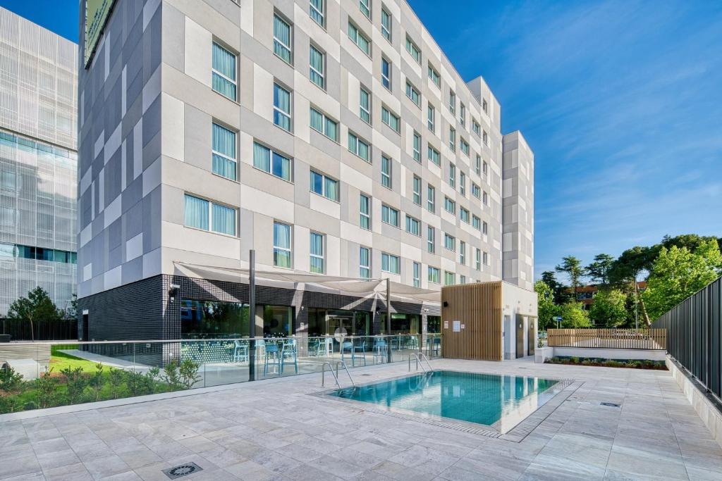 un hôtel avec une piscine en face d'un bâtiment dans l'établissement Holiday Inn Express - Madrid - Airport, an IHG Hotel, à Madrid