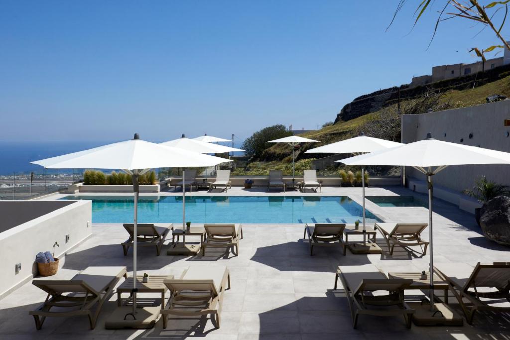 uma piscina com mesas, cadeiras e guarda-sóis em Mayu Suites em Pirgos