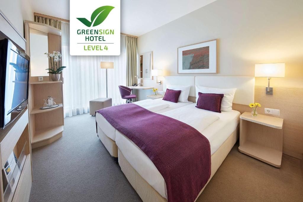 a hotel room with a large bed and a television at GHOTEL hotel & living Koblenz in Koblenz