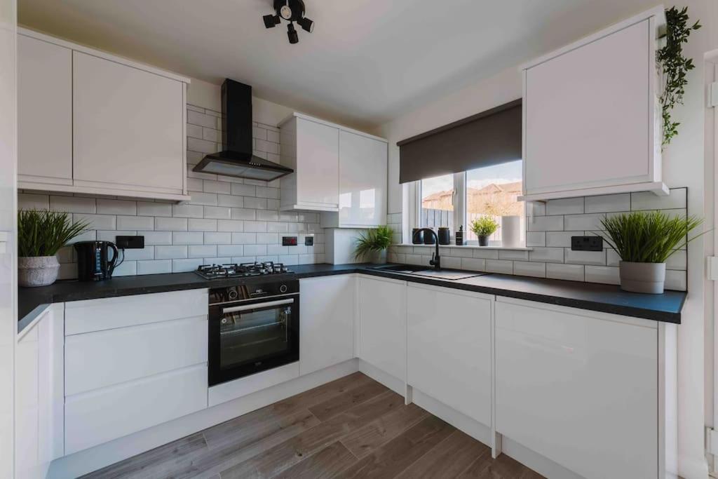 a kitchen with white cabinets and a stove top oven at ComfySleep ApartHOUSE in Glasgow