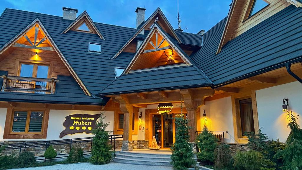 a house with a black roof with a front entrance at Dworek Myśliwski Hubert-świetna lokalizacja 50m od Term Bania in Białka Tatrzanska