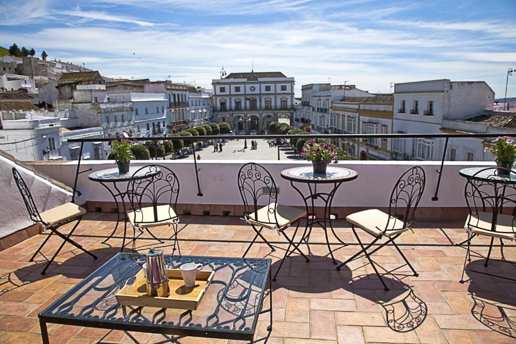 a balcony with tables and chairs and a view of a city at Apartamentos La Casa de la Alameda in Medina Sidonia