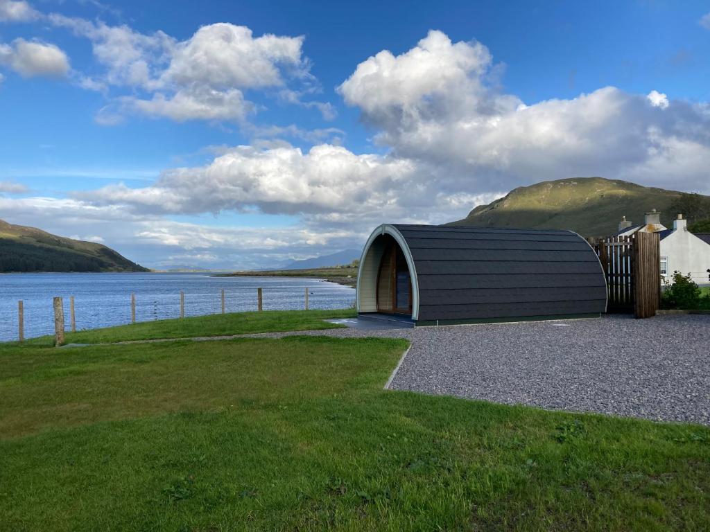 een klein gebouw naast een waterlichaam bij Sunset POD in Dunan