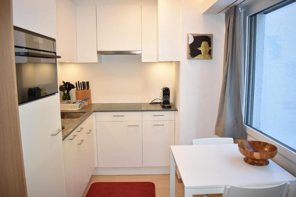 a kitchen with white cabinets and a table and a window at Seegarten A 110 Wy in Lenzerheide