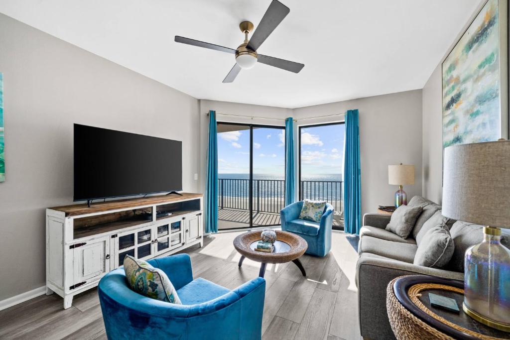 sala de estar con TV de pantalla plana y sillas azules en Phoenix VII 71113 by ALBVR - Beautiful Beachfront Condo with Amazing Views & Amenities! en Orange Beach