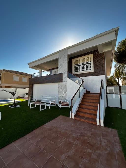 a house with stairs and chairs in the yard at Sea-side Villa in la Zenia in Alicante