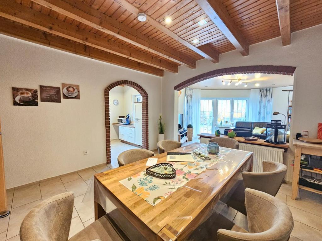 uma cozinha e sala de estar com uma mesa de madeira e cadeiras em Ferienhaus Merlin em Norden