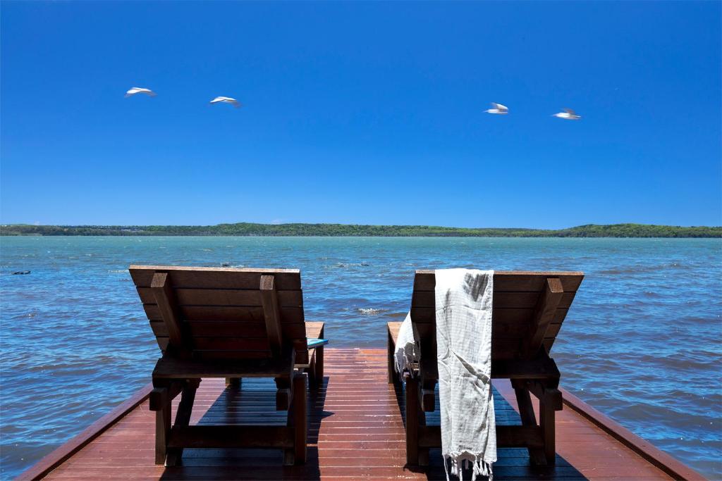 two chairs sitting on a dock on the water at Eumarella Shores Noosa Lake Retreat in Noosaville