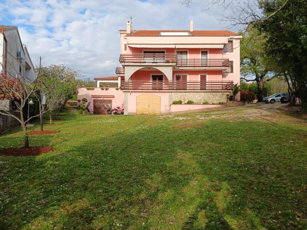 a large house with a green yard in front of it at Apartments by the sea Malinska, Krk - 19264 in Malinska