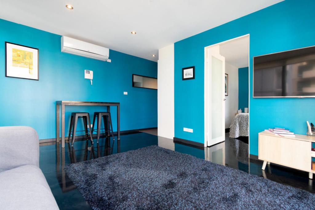 Sala de estar azul con sofá y mesa en Relaxing, light-filled city apartment, en Melbourne