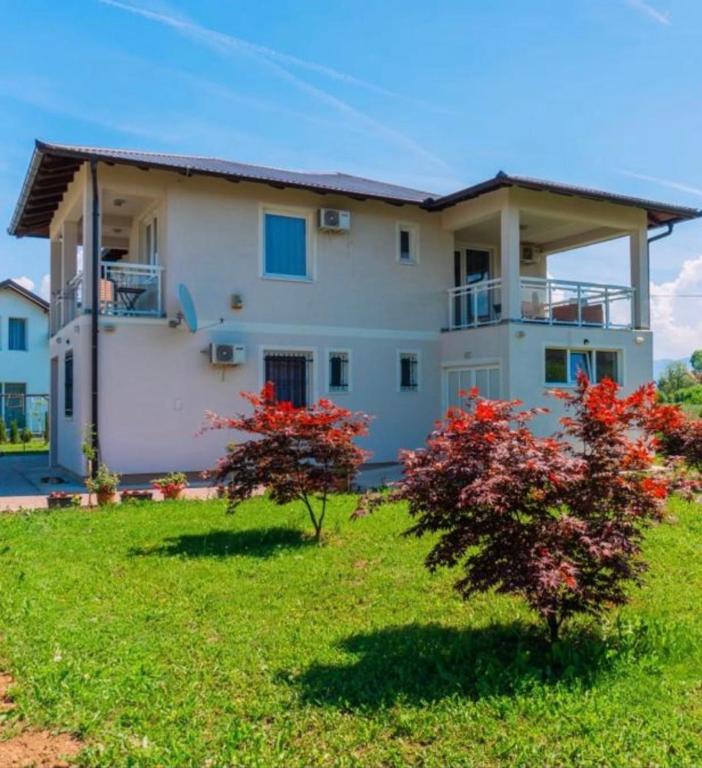 a large white house with red flowers in the yard at Dream Villa in Sarajevo