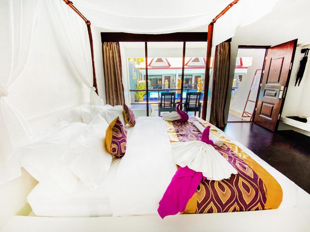 a bedroom with a large bed with white sheets and pink accessories at Carpe Diem Villas & Resort in Puerto Princesa City