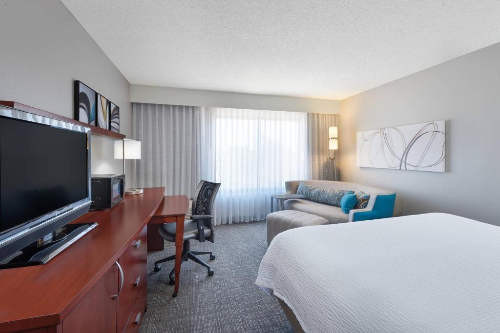 a hotel room with a bed and a desk with a television at Courtyard Harlingen in Harlingen