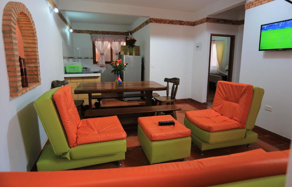 sala de estar con mesa, sillas y TV en Apartahotel La Gran Familia, en Villa de Leyva