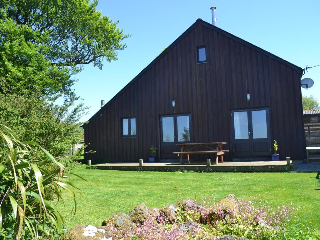 a black barn with a picnic table in front of it at Meader Barn in Marytavy