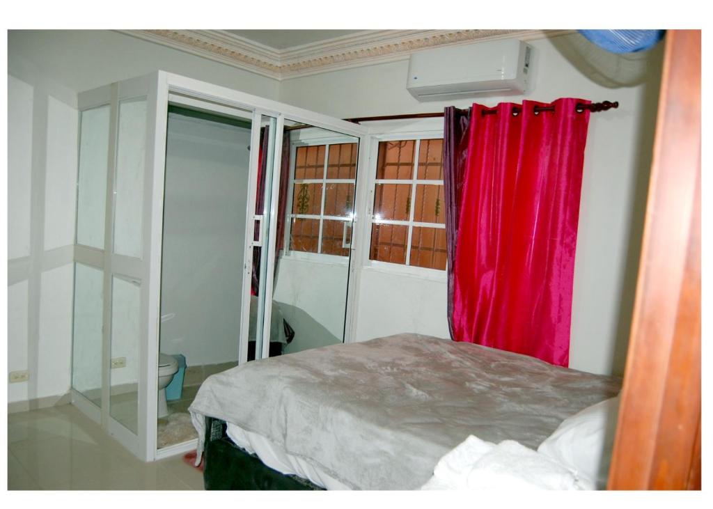 a bedroom with a red curtain and a bed at Haabitacion Estudio III in Baní