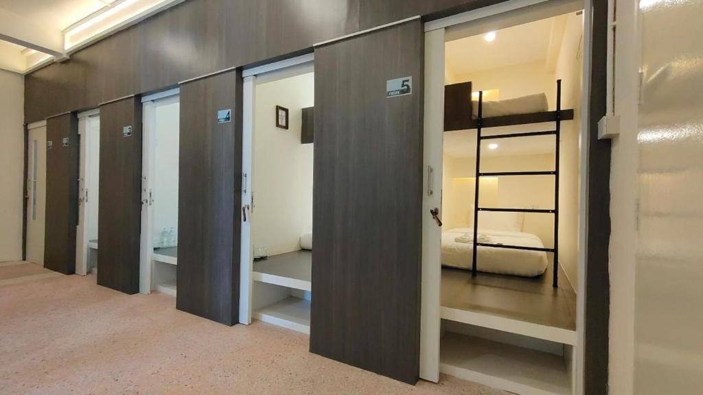 - une rangée de portes en verre dans une chambre avec un lit dans l'établissement Norm Space Hostel NST, à Nakhon Si Thammarat
