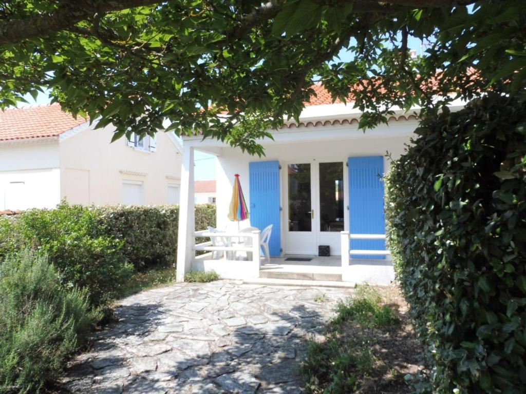 Casa blanca con puertas azules y silla en Maison Notre-Dame-de-Monts, 2 pièces, 4 personnes - FR-1-540-221, en Notre-Dame-de-Monts