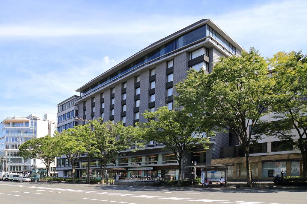 a tall building with trees in front of a street at Hotel Honnoji in Kyoto