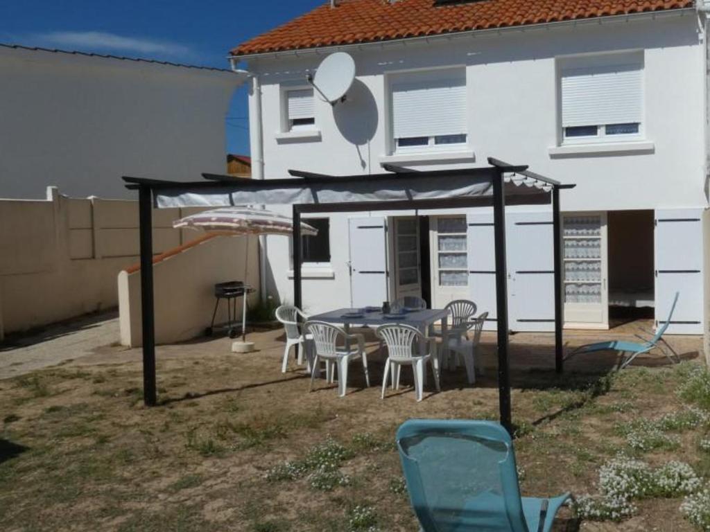 un patio avec une table et des chaises devant une maison dans l'établissement Maison 45m² à 100m de la plage avec jardin, Wifi et parking - 5 pers max - Animaux bienvenus - FR-1-540-233, à Notre-Dame-de-Monts
