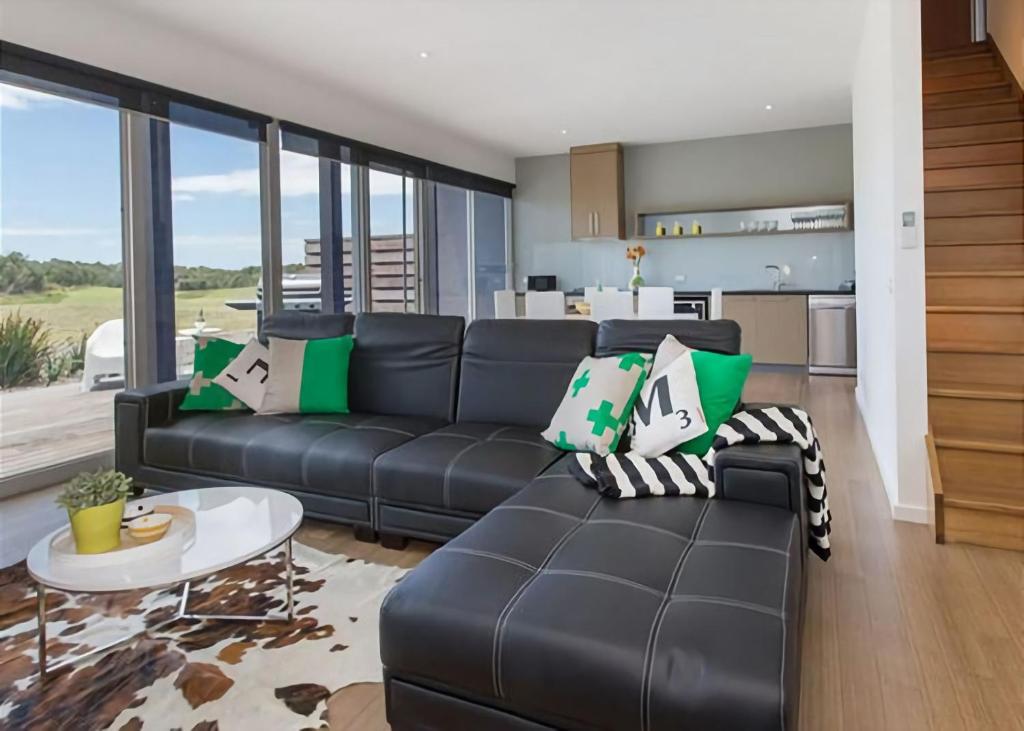 a living room with a black couch and a table at St Andrews Beach apartment 4 01 in Fingal