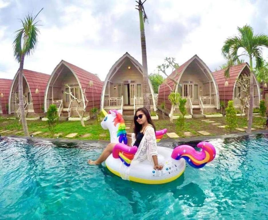 a girl sitting on a unicorn raft in a swimming pool at Daghan Cottage Nusa Penida in Nusa Penida