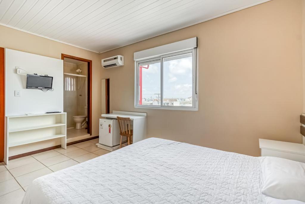 1 dormitorio con cama blanca y ventana en Hotel Pousada Vento Sul, en Río Grande