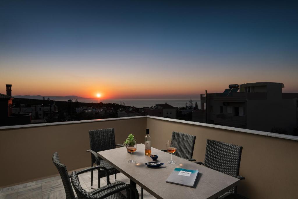 a table and chairs on a balcony with a sunset at Procris Villas Breathtaking Sea View in Kalathas