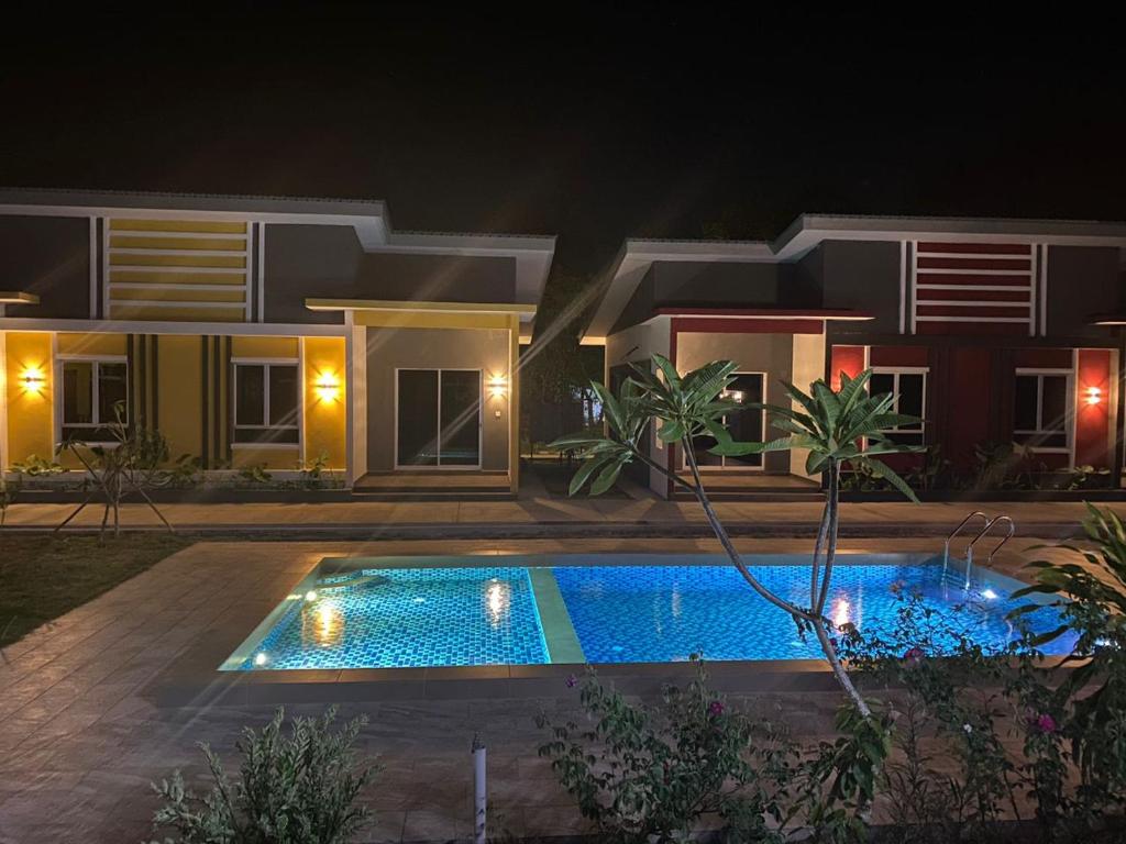 - une piscine en face d'une maison la nuit dans l'établissement Kedawang Village Langkawi, à Pantai Cenang