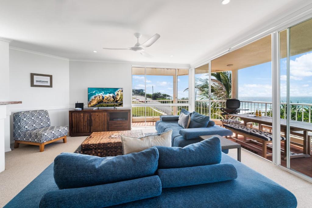 uma sala de estar com sofás azuis e uma varanda em Seamist 6 - Catch the Seamist from your penthouse em Sunrise Beach