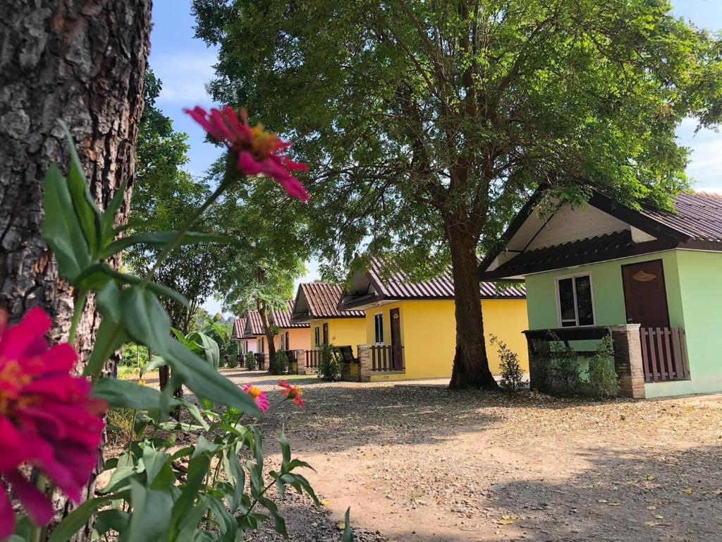 een huis met een boom en bloemen ervoor bij Ban Rai Plai Na บ้านไร่ปลายนารีสอร์ท 