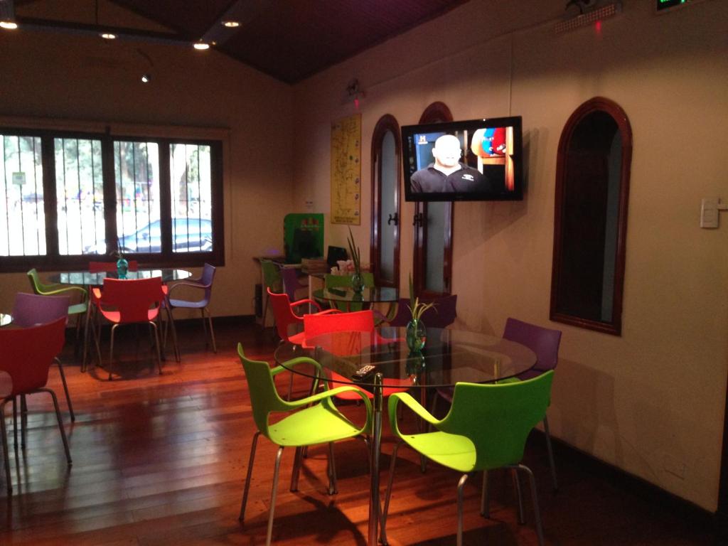 a room with a table and chairs and a tv on the wall at La Posada del Parque in Salta