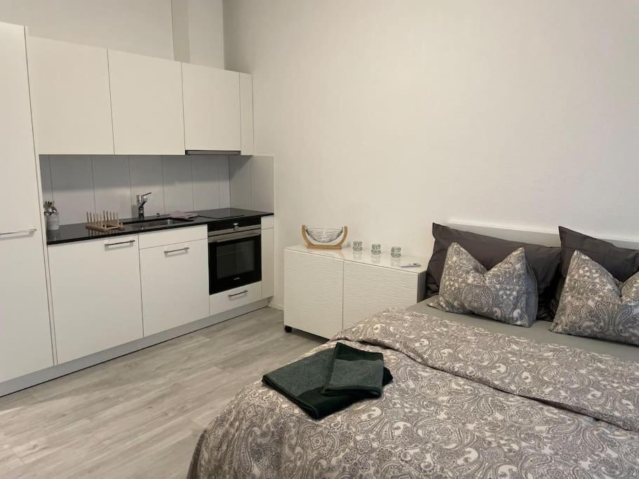 a bedroom with a bed and a kitchen with white cabinets at Studio in neuem EFH (2023) in Elsau