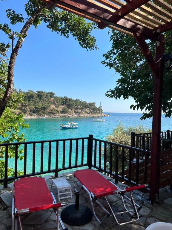two red chairs and a table on a balcony overlooking the water at Aliki Stone House in Alyki