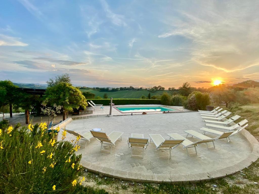 a group of chairs and a swimming pool with the sunset at Il Melograno Country Resort in Grottazzolina