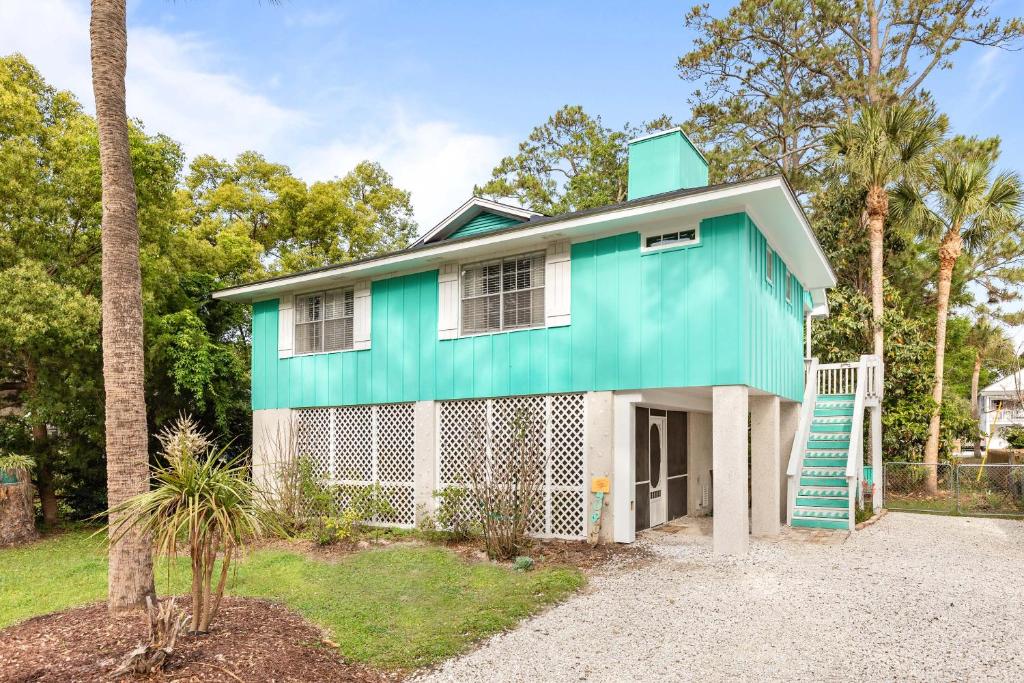 a green and white house with a palm tree at Castaway Cottage in Tybee Island